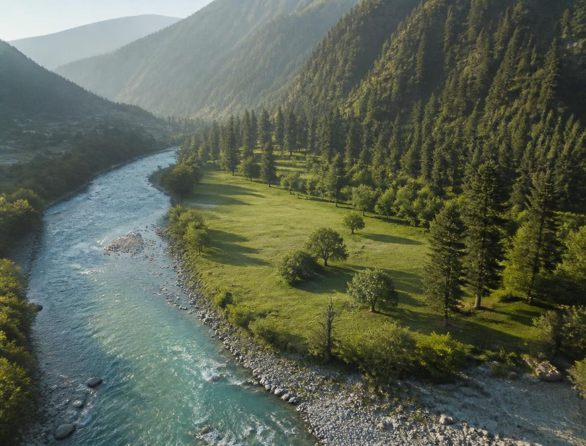 Green riverside land beside a turquoise river in the Swat valley